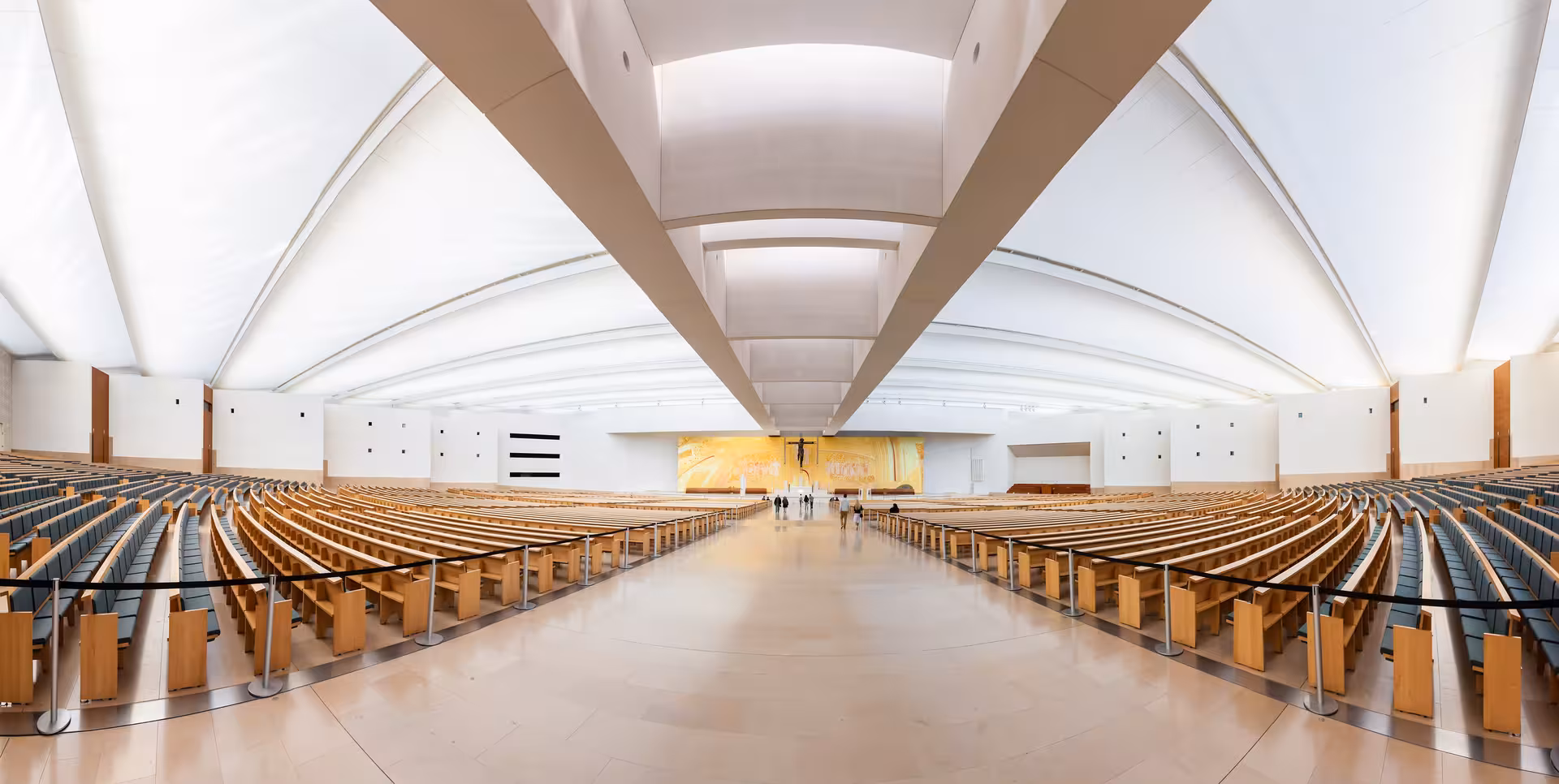 Interior of the modern Basilica of the Holy Trinity in Fátima, featuring expansive seating and bright architecture.