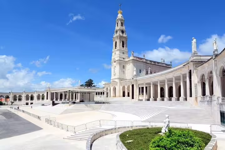 Panoramic view of Fatima's Basilica, showcasing its grand architecture and open plaza under a clear blue sky.