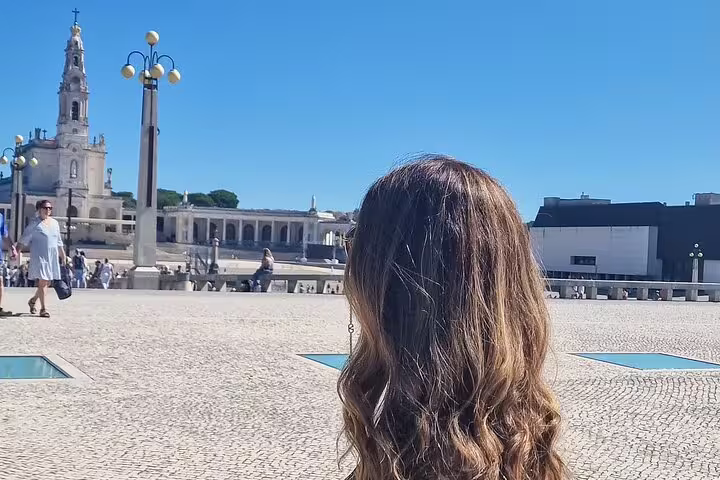 Visitor admires the stunning Basilica of Our Lady of Fatima under a clear blue sky on a full-day private tour from Lisbon.