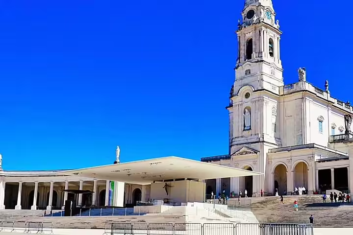 The grand Basilica of Our Lady of the Rosary of Fatima under a clear blue sky, highlighting its stunning architecture.