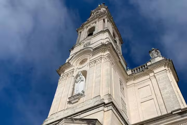 View of the stunning Fátima Basilica tower under a blue sky, featured in our small group day trip from Lisbon tour.