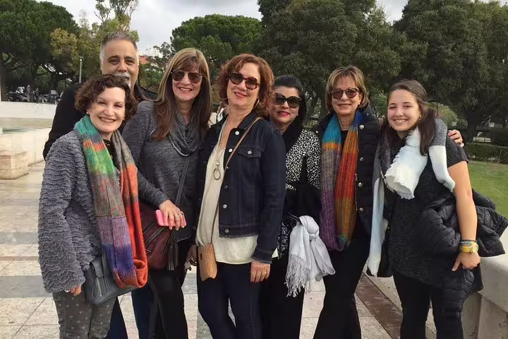 Group of happy tourists enjoying a Fátima and Óbidos small group day tour, surrounded by lush greenery and vibrant scarves.