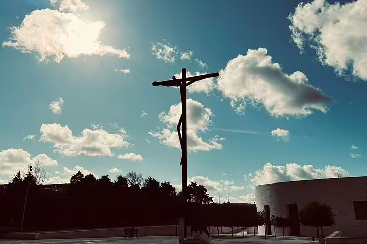 Silhouette of a cross against a vibrant blue sky in Fátima, capturing the spiritual essence of a full-day tour to Fátima, Nazaré, and Óbidos.