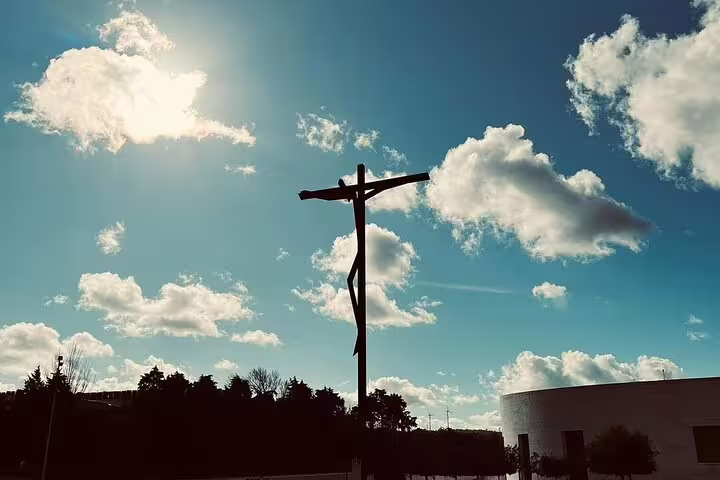 Silhouette of a cross against a blue sky with clouds in Fátima, perfect for a spiritual day trip from Lisbon in small groups.