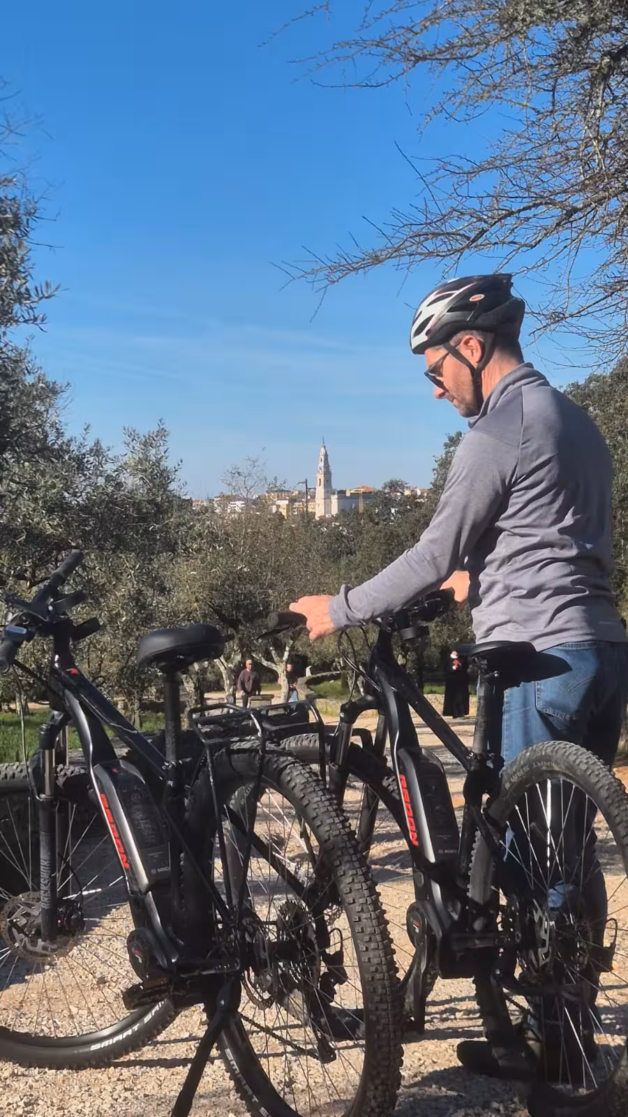 Rider with electric bikes on a countryside trail near Fátima, with Sanctuary skyline views on the guided e-bike tour