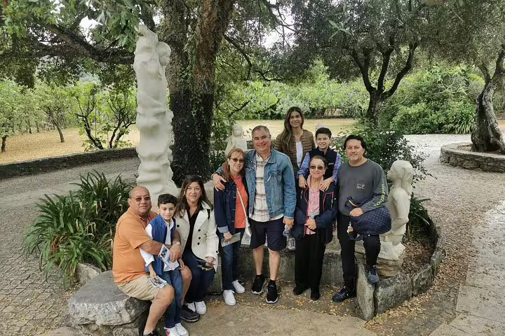 Group enjoying a scenic Fatima full-day private tour from Lisbon, surrounded by lush greenery and unique sculptures.
