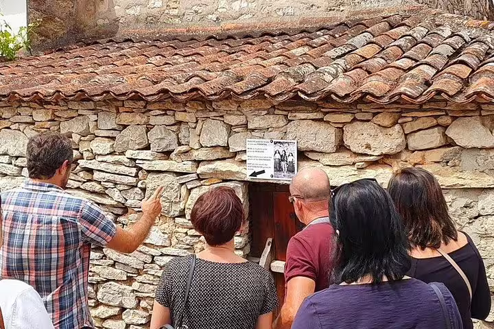 Visitors learning about a historic stone house in Fátima on the full-day private tour from Porto to Fátima & Coimbra.