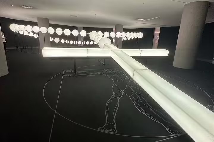 Modern art installation featuring a glowing cross and circular lights at a museum in Fátima, Portugal, during a Lisbon day trip.