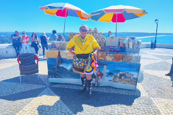 Colorful local vendor in traditional attire selling regional snacks in Fátima, showcasing vibrant Portuguese culture.