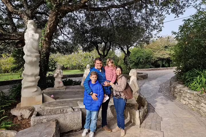 Family enjoying a scenic moment at a historic site during the Fatima Full-Day Private Tour from Lisbon, surrounded by nature and statues.
