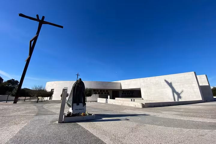 Modern architecture and statue at Fatima Sanctuary under a bright sky, featured in Lisbon to Fatima group tour.