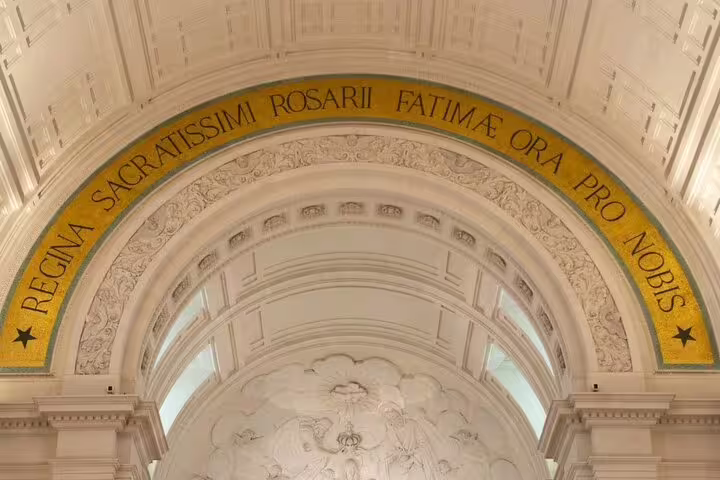 Intricate archway with Latin inscription at Fátima Sanctuary, featured on small group day trips from Lisbon for cultural exploration.