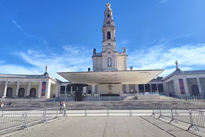 View of the iconic Fátima Sanctuary with its towering basilica under a clear blue sky, a key pilgrimage site in Portugal.