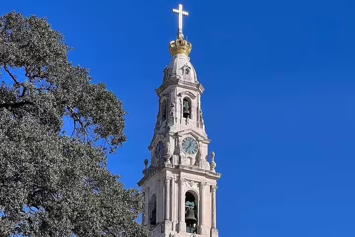 Majestic view of Fátima Sanctuary bell tower under clear blue skies, ideal for a small group day trip from Lisbon.