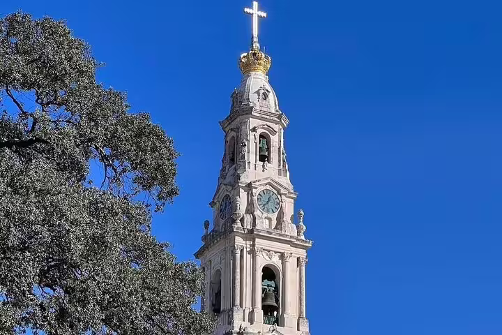 Majestic view of the Sanctuary of Fátima's bell tower under a clear blue sky, ideal for a small group day trip from Lisbon.