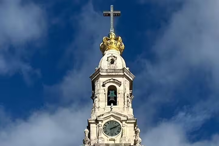 Stunning view of the Sanctuary of Fátima's iconic bell tower against a blue sky, featured in our small group day trip from Lisbon.
