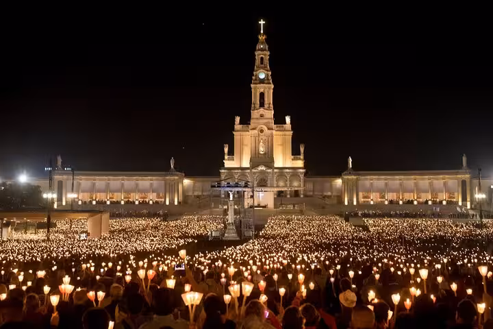 Candlelit night pilgrimage at the Sanctuary of Fatima, showcasing its majestic illuminated facade.