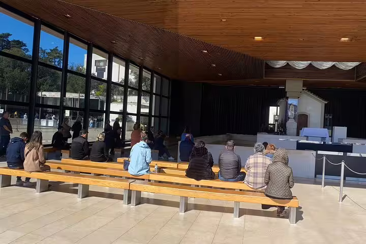 Visitors seated inside a modern chapel at the Sanctuary of Fátima, highlighting the serene atmosphere and architecture.