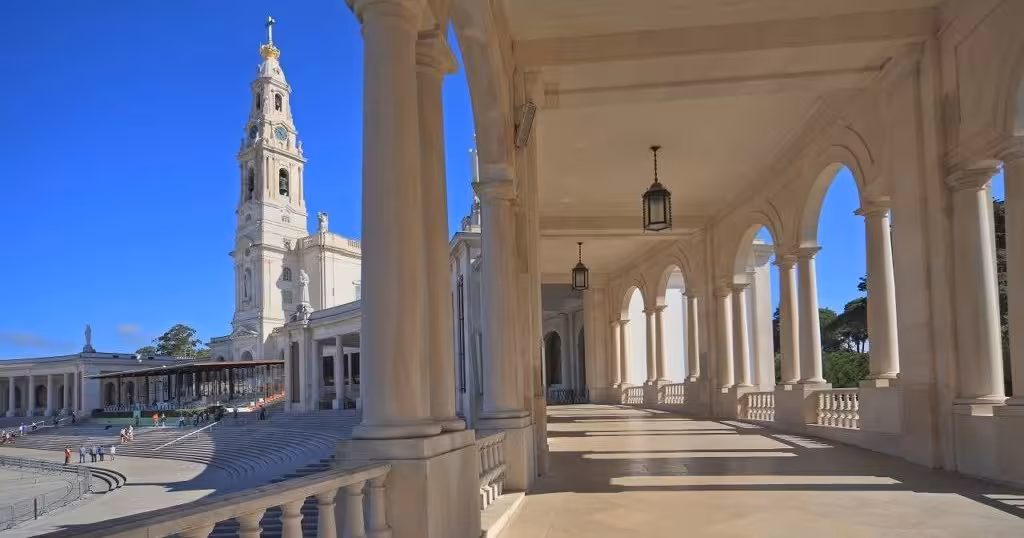 Colonnade walkway at Fátima Sanctuary with basilica tower, featured on private Fátima and Coimbra tour with lunch