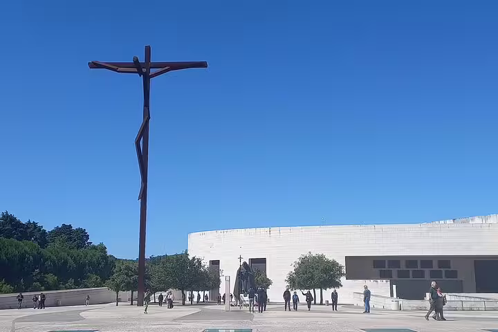 Visitors admire the modern crucifix at the Sanctuary of Fátima, a highlight of the Fatima-Nazare-Obidos tour from Lisbon.