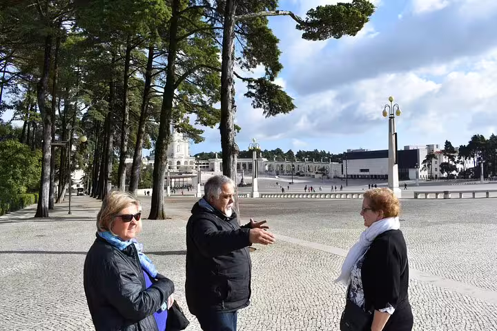 Visitors enjoy a guided tour at Fátima Sanctuary, capturing the vibrant atmosphere of the Fátima and Óbidos Small Group Day Tour.