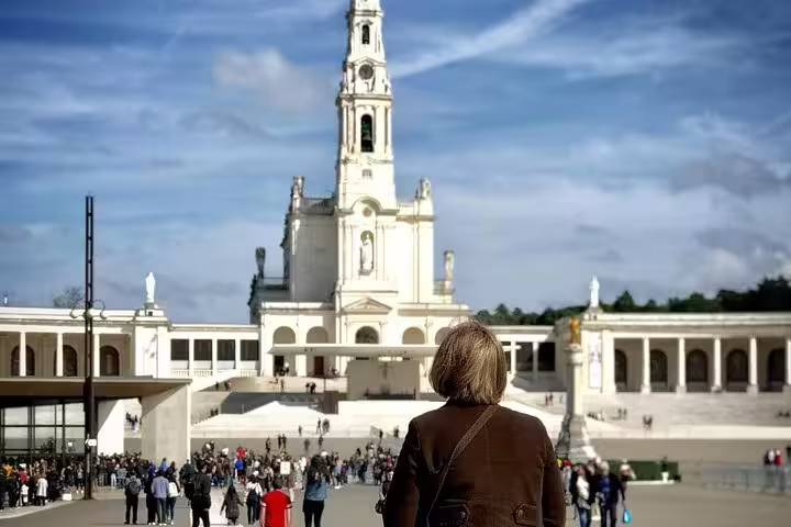 Visitor admiring the Sanctuary of Fátima on a sunny day, a highlight of the Private Tour Fátima, Nazaré & Óbidos from Lisbon.