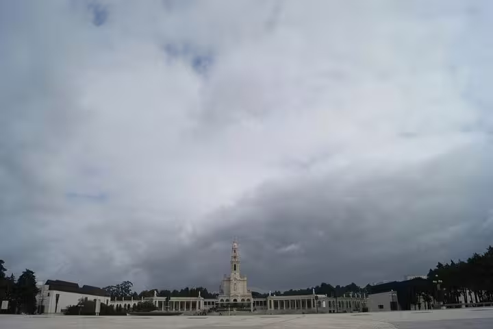 Panoramic view of Fátima Sanctuary under a dramatic cloudy sky, a must-visit on Lisbon day trips.