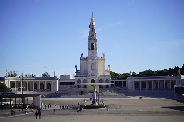 The majestic Sanctuary of Our Lady of Fatima under clear blue skies, a highlight of the Fatima, Nazare, and Obidos tour from Lisbon.