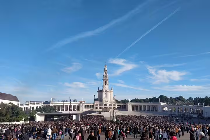 Crowds gather at the Sanctuary of Fátima under a clear blue sky, a key stop on the private Lisbon to Porto transfer tour.