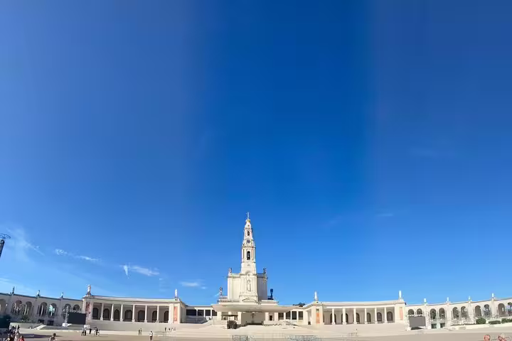 Panoramic view of the Sanctuary of Our Lady of Fatima under a clear blue sky, a highlight on the Fatima tour from Lisbon.