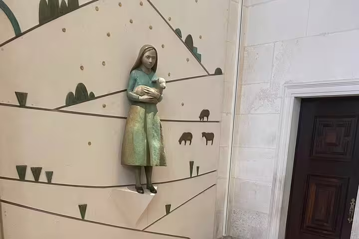Artistic statue of a shepherd girl holding a lamb, representing the Pastorinhos at Fátima Sanctuary.
