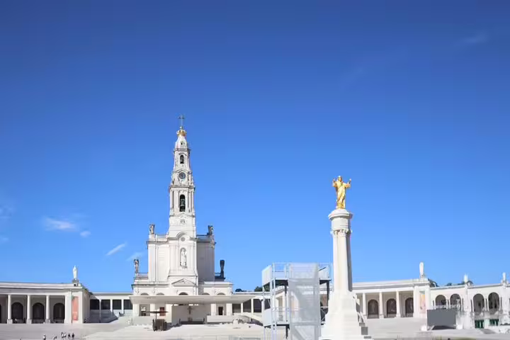 Explore the iconic Fátima Sanctuary's grand architecture under a clear blue sky on a private Portugal tour.