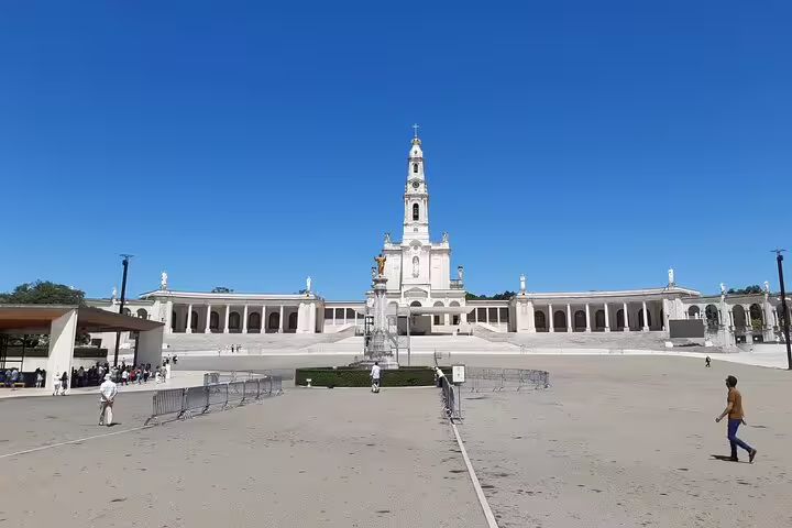 Sanctuary of Fátima under clear blue skies, showcasing its grand architecture, a highlight of Portugal's private cave and religious tours.