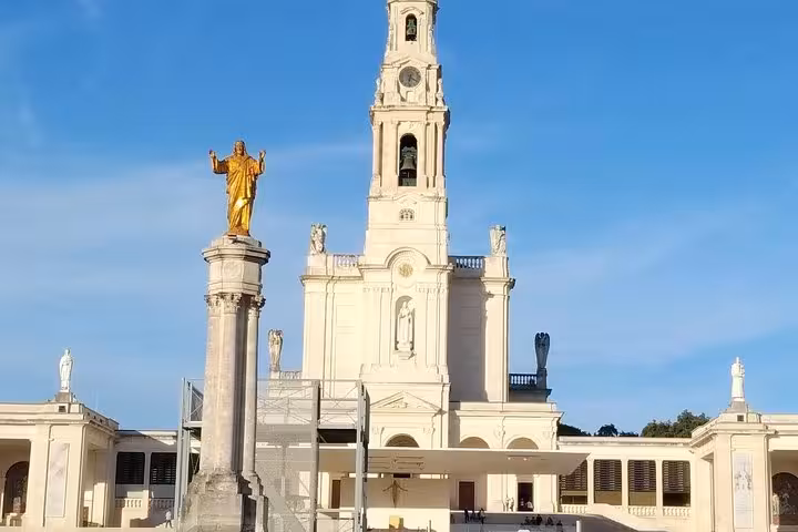 Sanctuary of Fátima with iconic golden statue under clear blue sky, ideal for private tours in Portugal.
