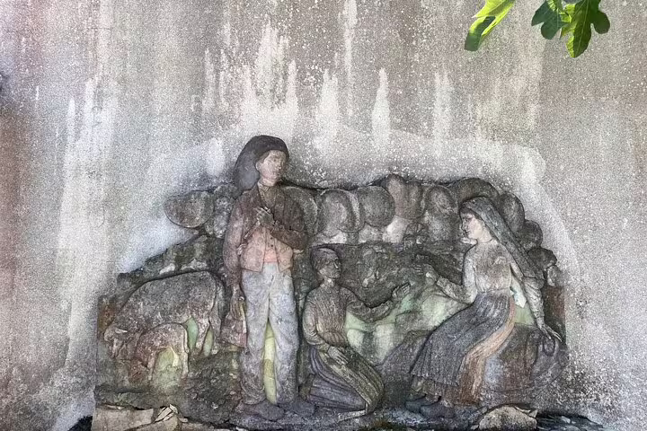 Historic stone relief depicting the three shepherd children of Fátima, a significant religious site in Portugal.