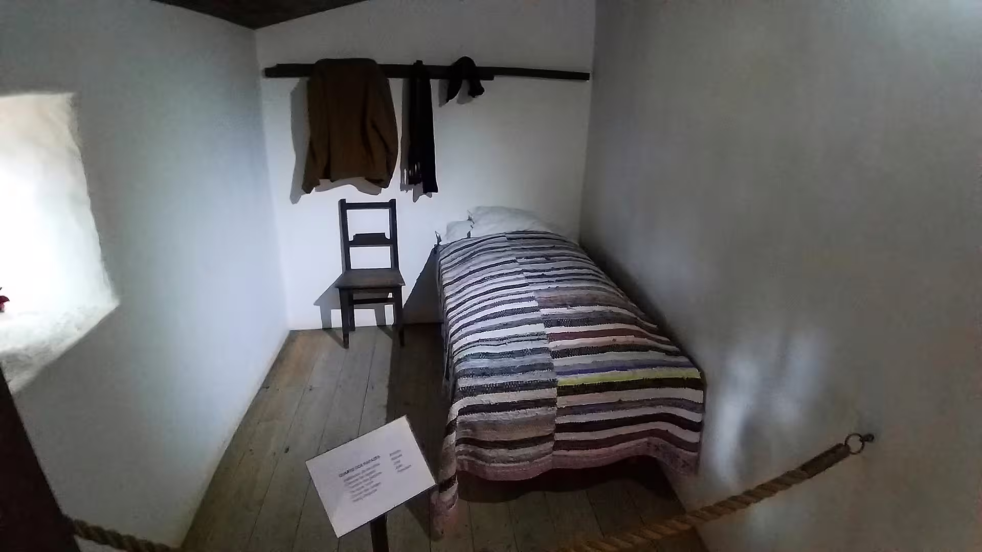 Simple rustic bedroom of a Little Shepherds House in Fátima, featuring a striped bedspread and wooden chair, Portugal tour.