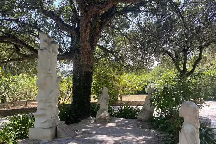 Peaceful garden with statues of the Fatima shepherd children under an ancient tree, part of a Lisbon tour experience.