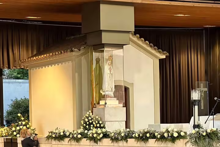 Statue of Our Lady of Fatima adorned with flowers inside the Little Shepherds' House, a spiritual highlight of the tour.