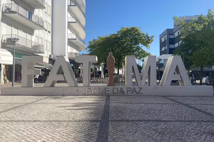 Stylized Fatima sign in a bustling plaza, showcasing the city's welcoming atmosphere on the Fatima tour from Lisbon.