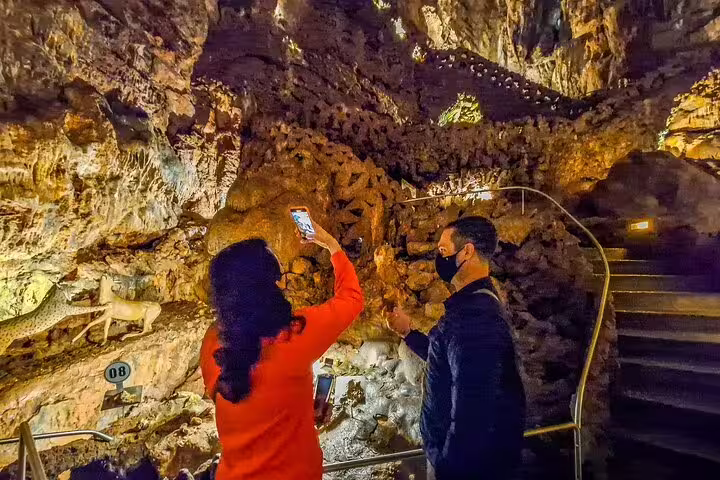 Tourists explore a stunning cave formation on the Biggest Caves in Portugal and Fatima full-day private tour from Lisbon.