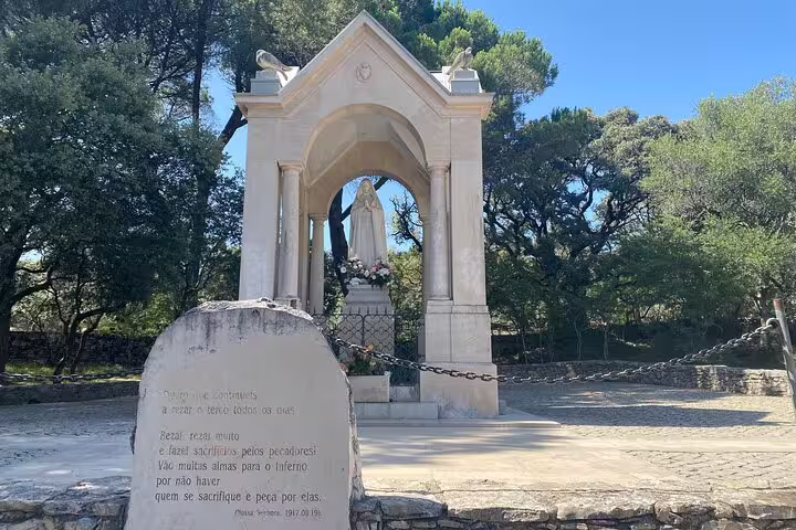 Statue of Our Lady of Fatima surrounded by trees in Little Shepherds' Village, a serene pilgrimage site in Portugal.