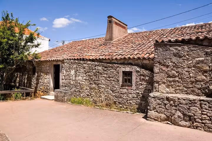 Charming stone cottage in Fátima, Portugal, showcasing traditional architecture under a clear blue sky.