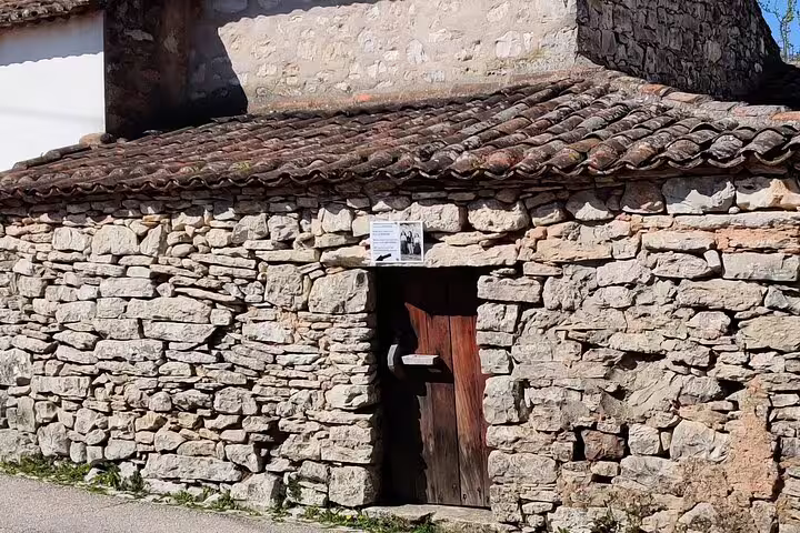 Rustic stone building with wooden door in Fatima, showcasing traditional architecture on a private day tour in Portugal.