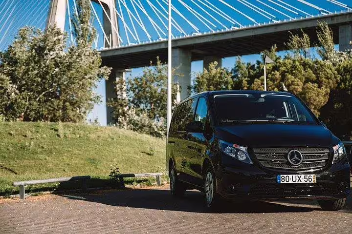 Comfortable black van ready for the Fátima and West coast of Portugal private tour, parked near a scenic bridge.