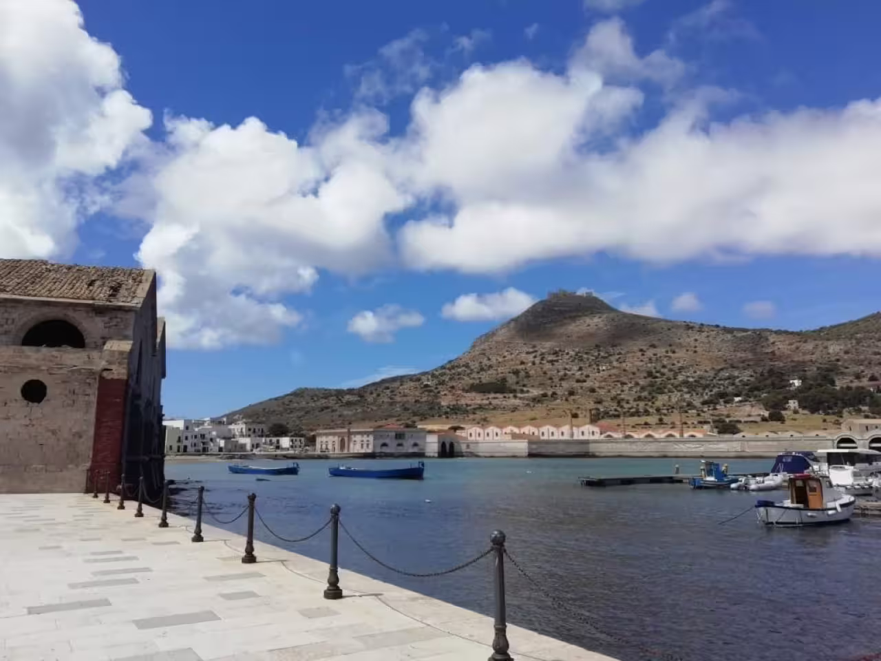 Favignana harbor promenade with fishing boats and Mount Santa Caterina, Egadi Shuttle Tour stop