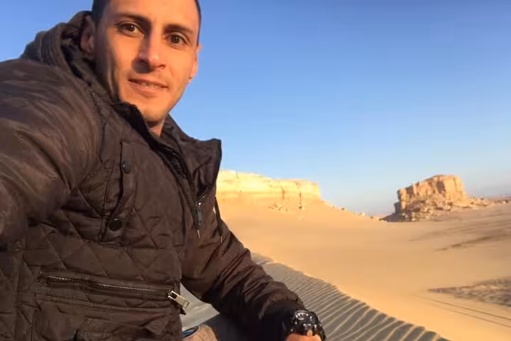 Tourist relaxes in Fayoum's serene desert landscape, capturing moments on a private Jeep tour from Cairo.
