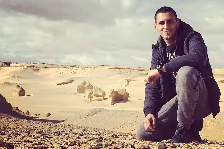 Adventurer kneeling in the rocky desert terrain of Fayoum Oasis on a guided Jeep tour from Giza.