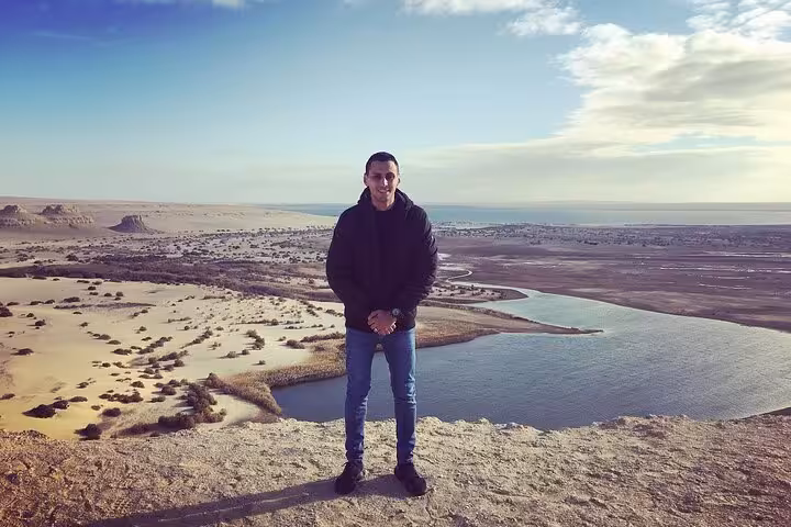 Tourist posing with a scenic view of Fayoum Oasis' lakes and desert landscape on a private tour.