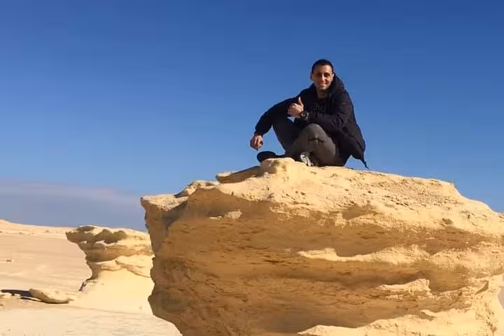 Traveler enjoys panoramic view atop rock formation in Fayoum Oasis during private Jeep tour from Cairo.