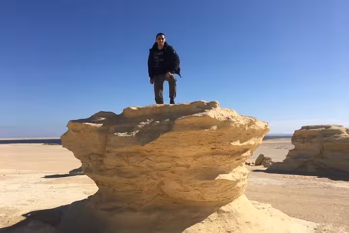 Adventurer stands on unique sandstone in Fayoum Oasis, highlighting Egypt's desert beauty on a Jeep tour.